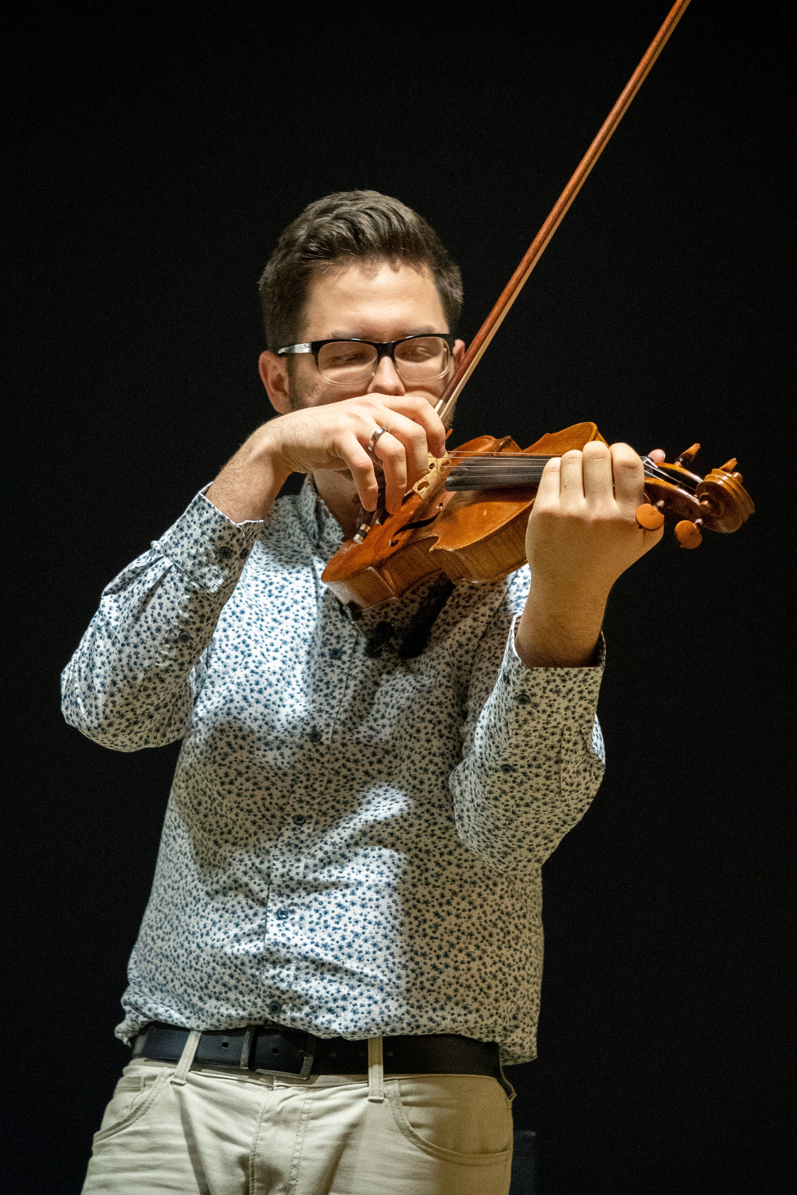 Mike holding his violin ready to play with the frog of his bow right in front of his face