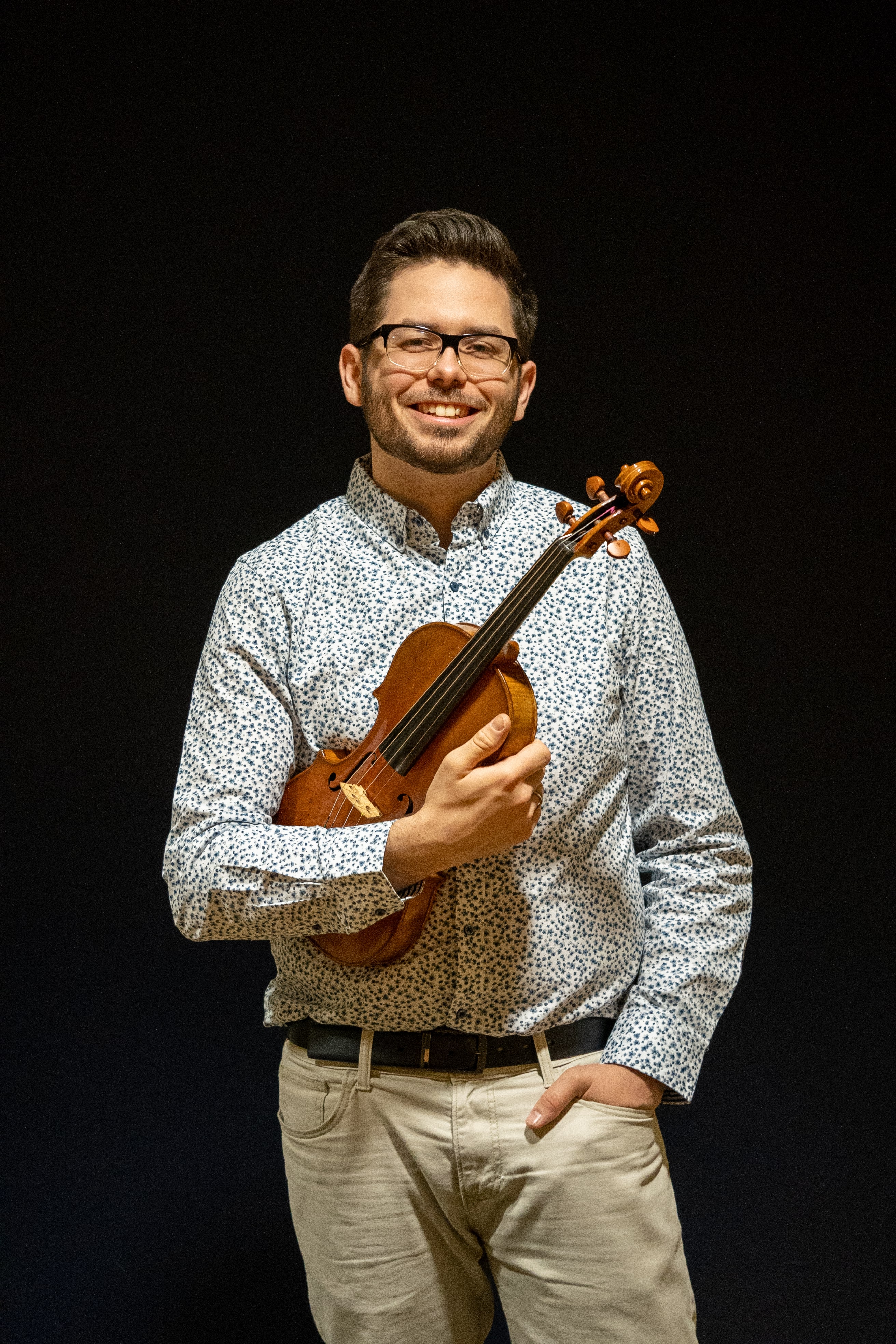 Mike smiling with his violin in hand, facing the camera