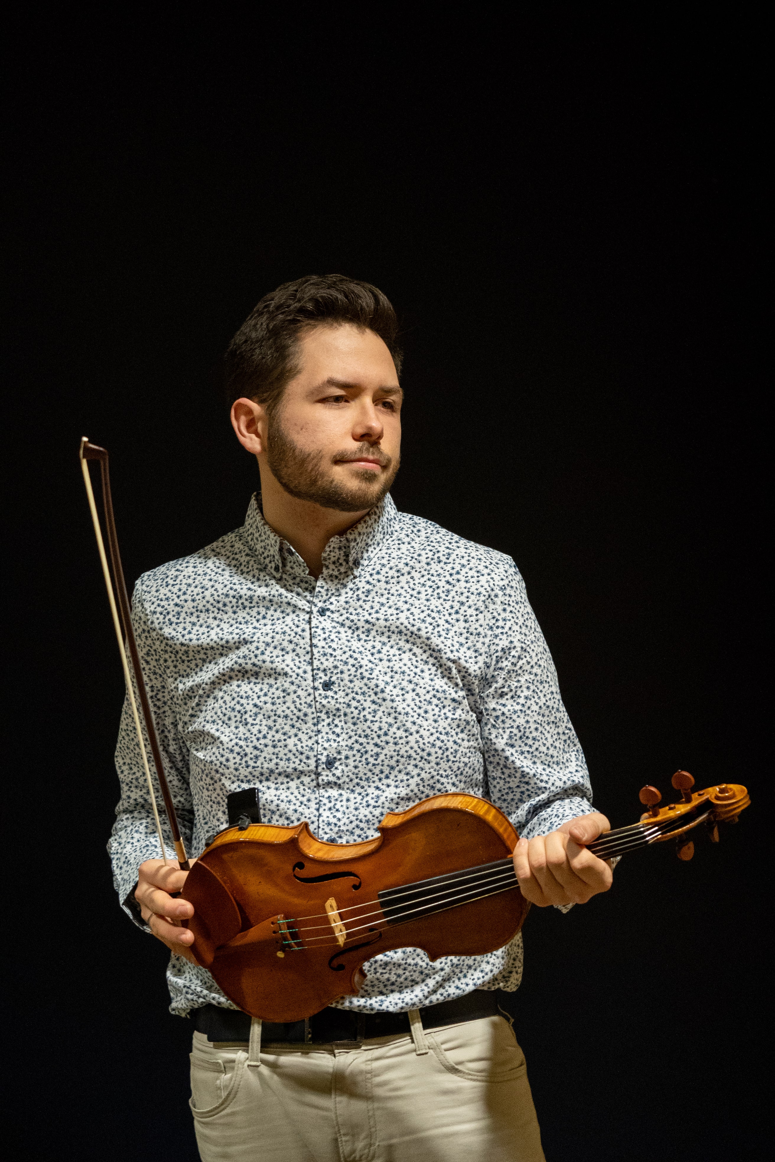 Mike holds his violin looking in the distance